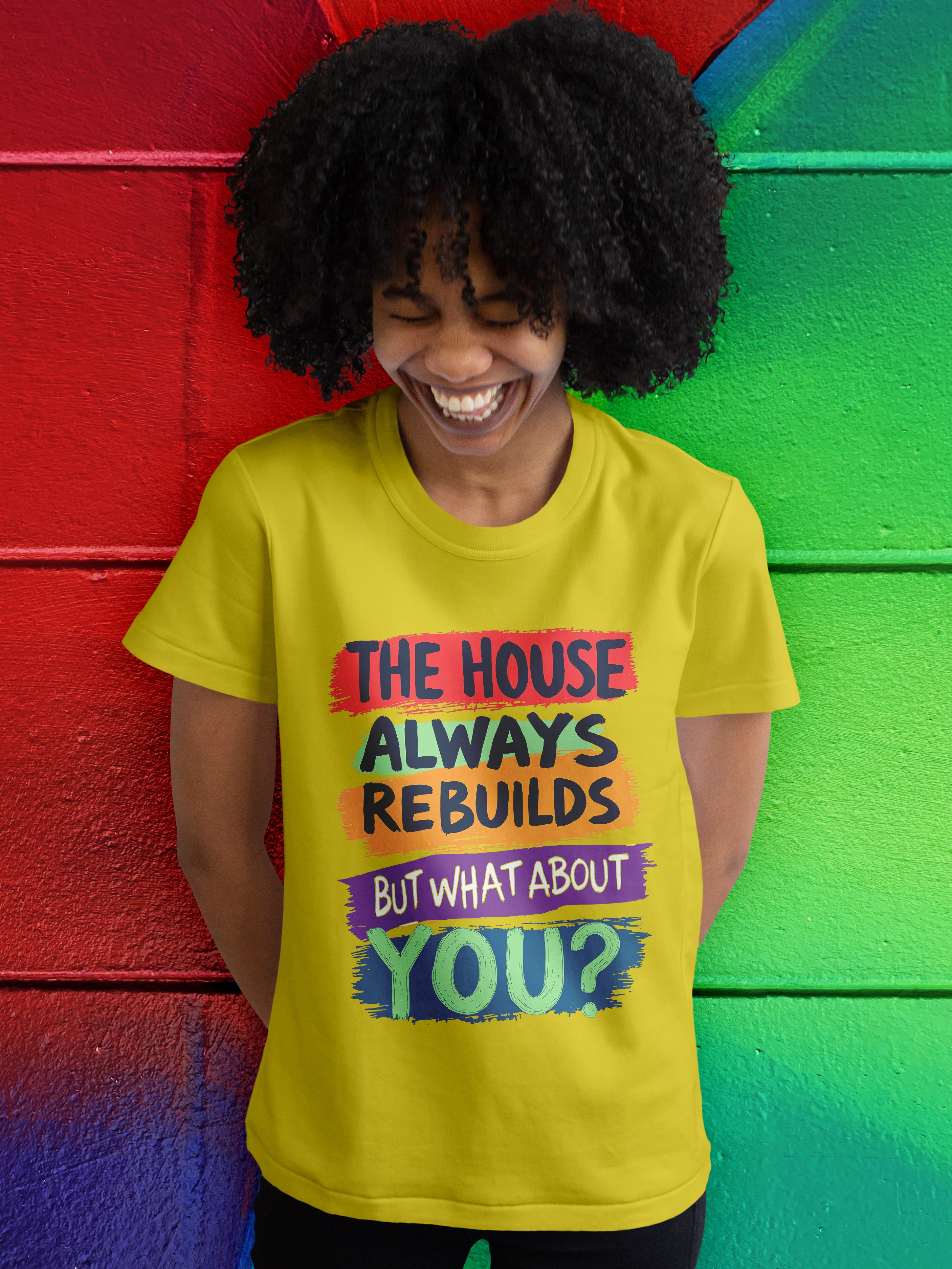 Person wearing a yellow t-shirt with motivational quote against a colorful wall.